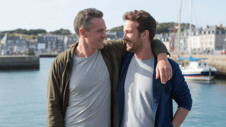 Deux hommes adultes marchent au port de Lorient au coucher du soleil, dans une scène naturelle et réaliste illustrant une atmosphère accueillante en Bretagne sud.